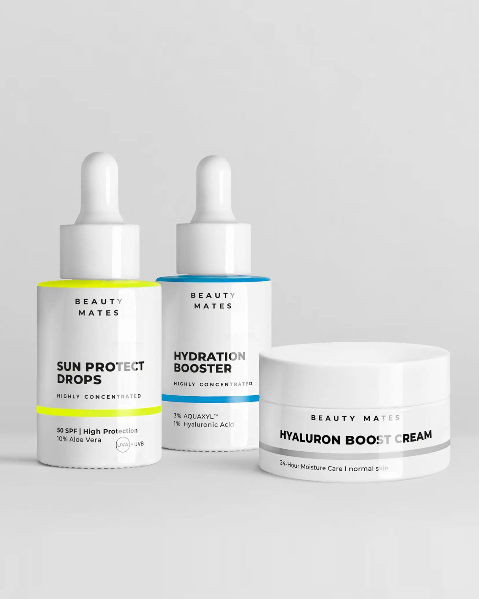 Beauty Mates Sun Protect Drops, Hydration Booster und Hyaluron Boost Cream nebeneinander auf grauem Hintergrund.